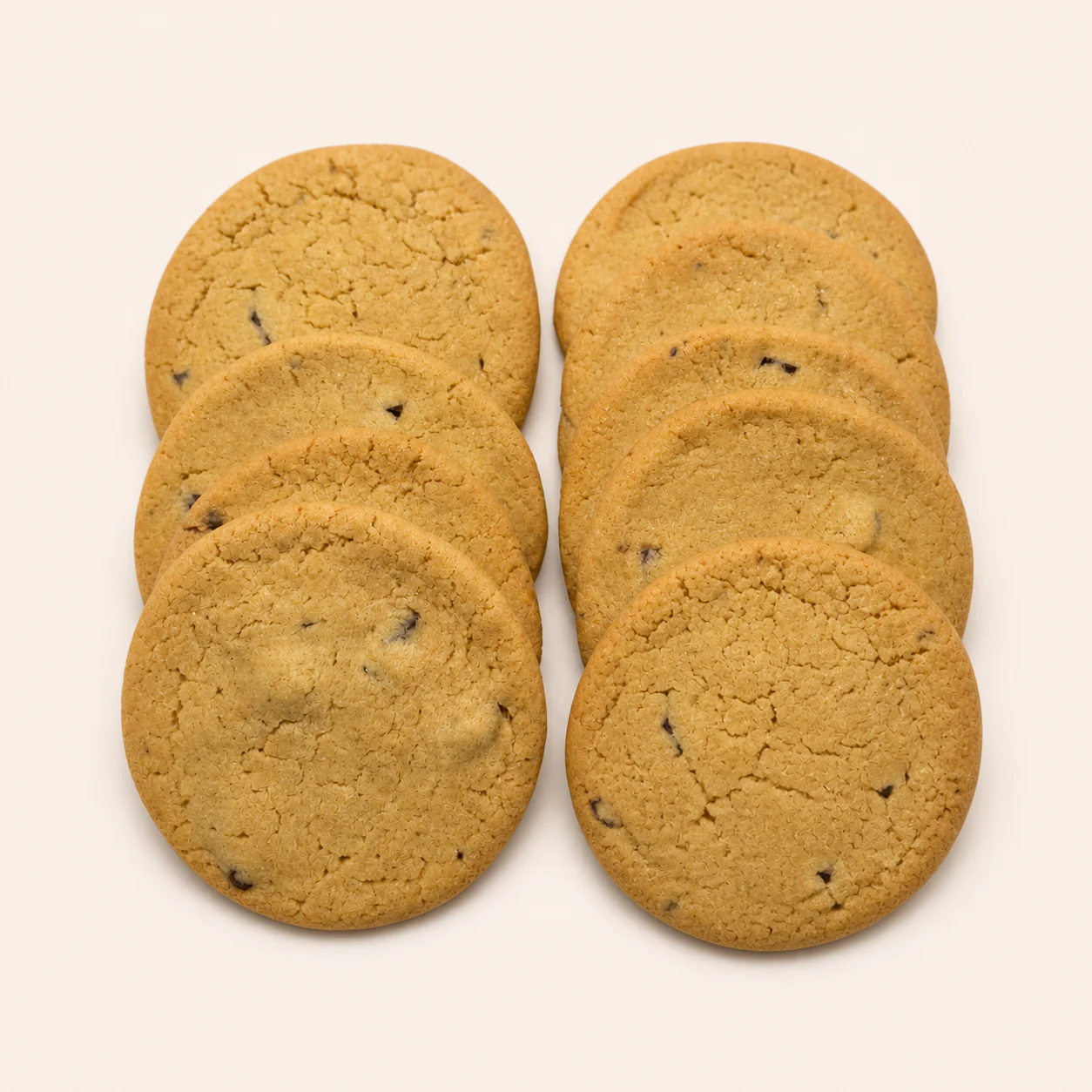 Eight chocolate chip cookies arranged on a pale studio background